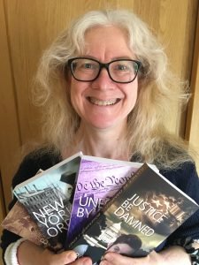 Rosemary J. Kind holding the books in the Flynn and Reilly series of which Justice Be Damned is the fourth.